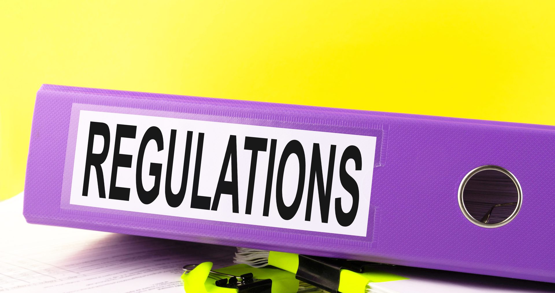 The Regulations text is written on an office folder on a pile of papers with a yellow background. Copy space.
